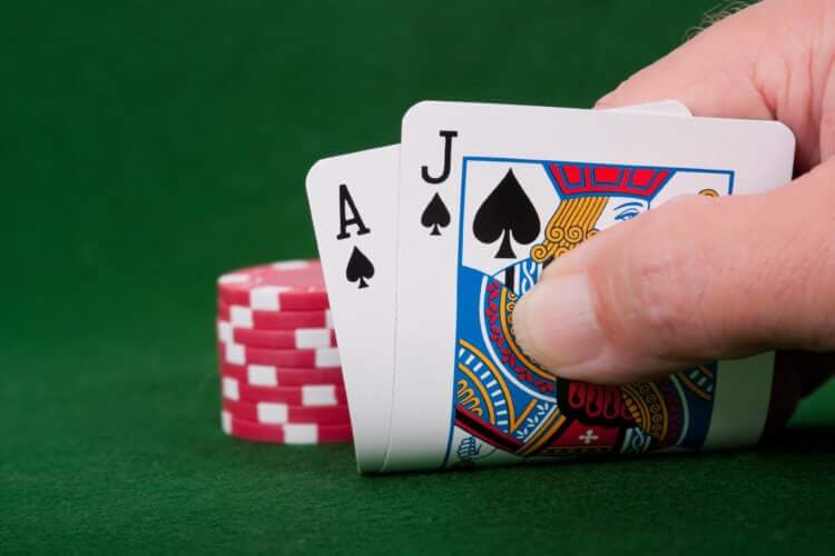 Image of a person holding a pair of cards and some poker chips in the background